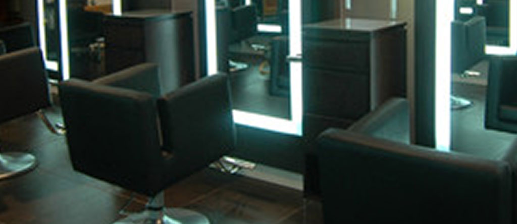 An empty modern hair salon with black chairs and illuminated mirrors, specializing in hair treatments. - Scott J Salons in New York, NY