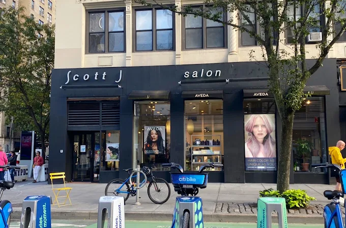 Street view of a hair salon named "Scott J Salon" with large posters in the windows and Citi Bike rentals parked outside on the curb. - Scott J Salons in New York, NY
